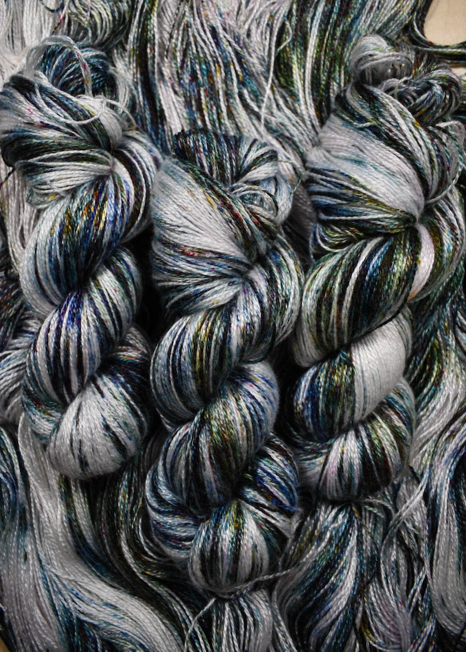 Bamboo sock yarn hand dyed with green speckles.