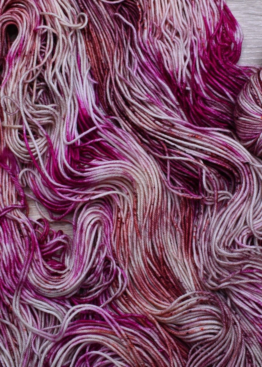 Hand dyed pink speckled merino wool yarn.
