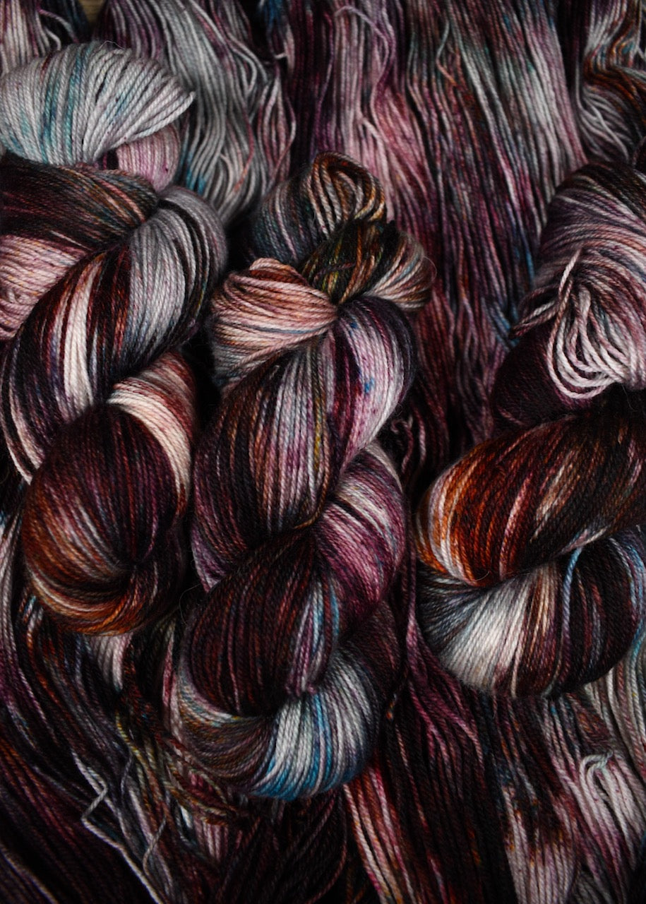 Hand dyed wool sock yarn with blue and red speckles.