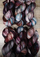 Hand dyed wool sock yarn with blue and red speckles.