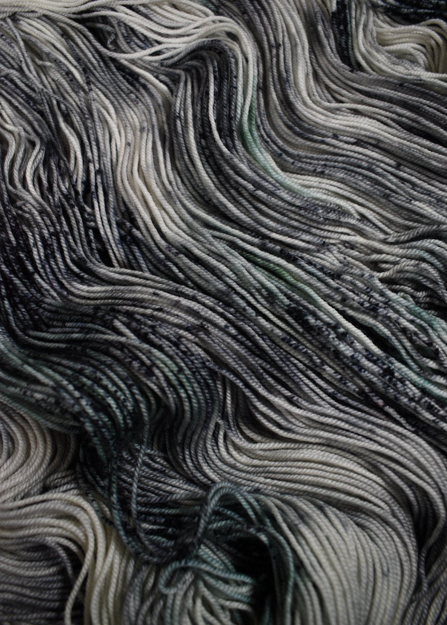 Gray and light green speckled hand dyed merino and cashmere sock yarn.