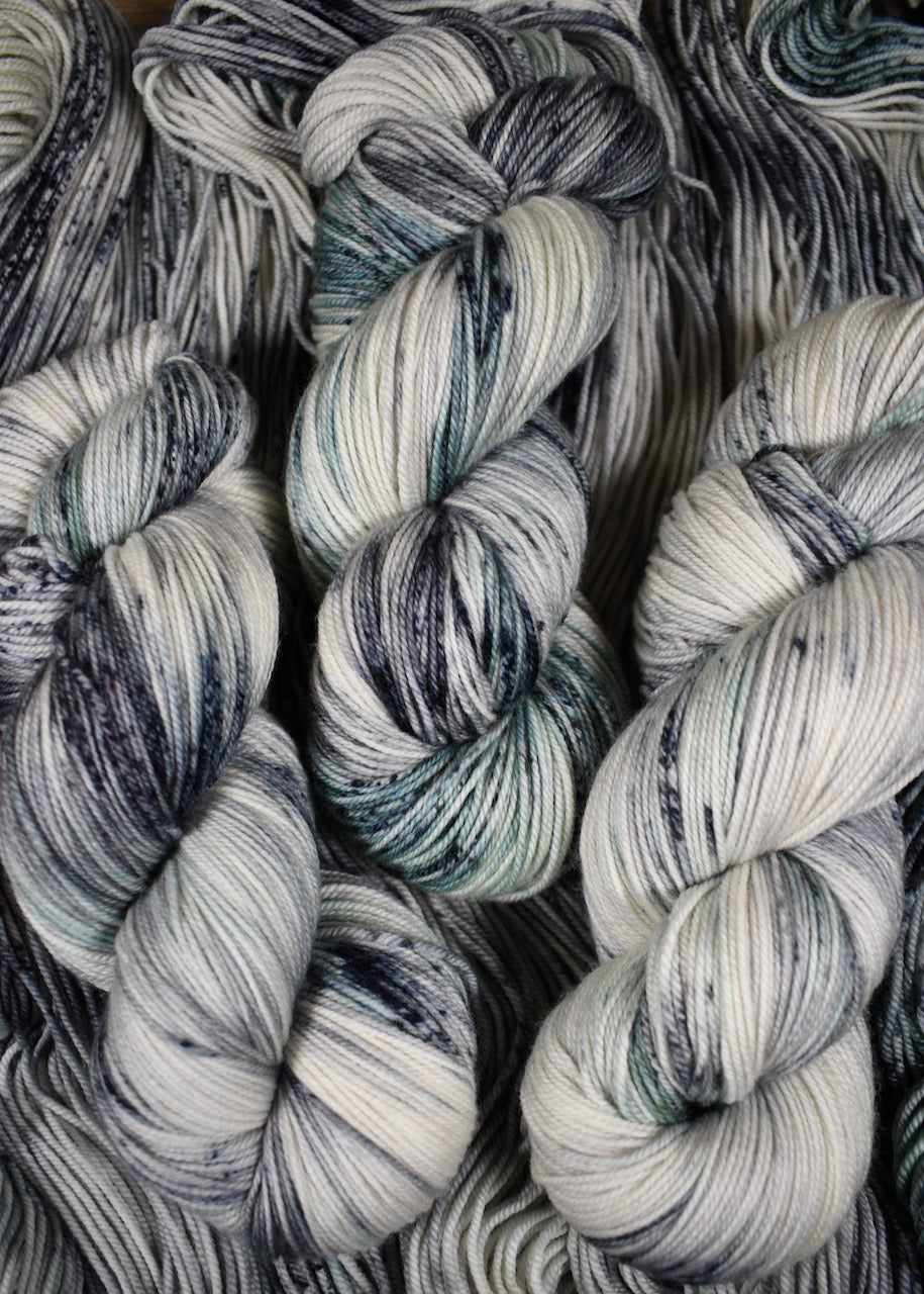 Gray and light green speckled hand dyed merino and cashmere sock yarn.