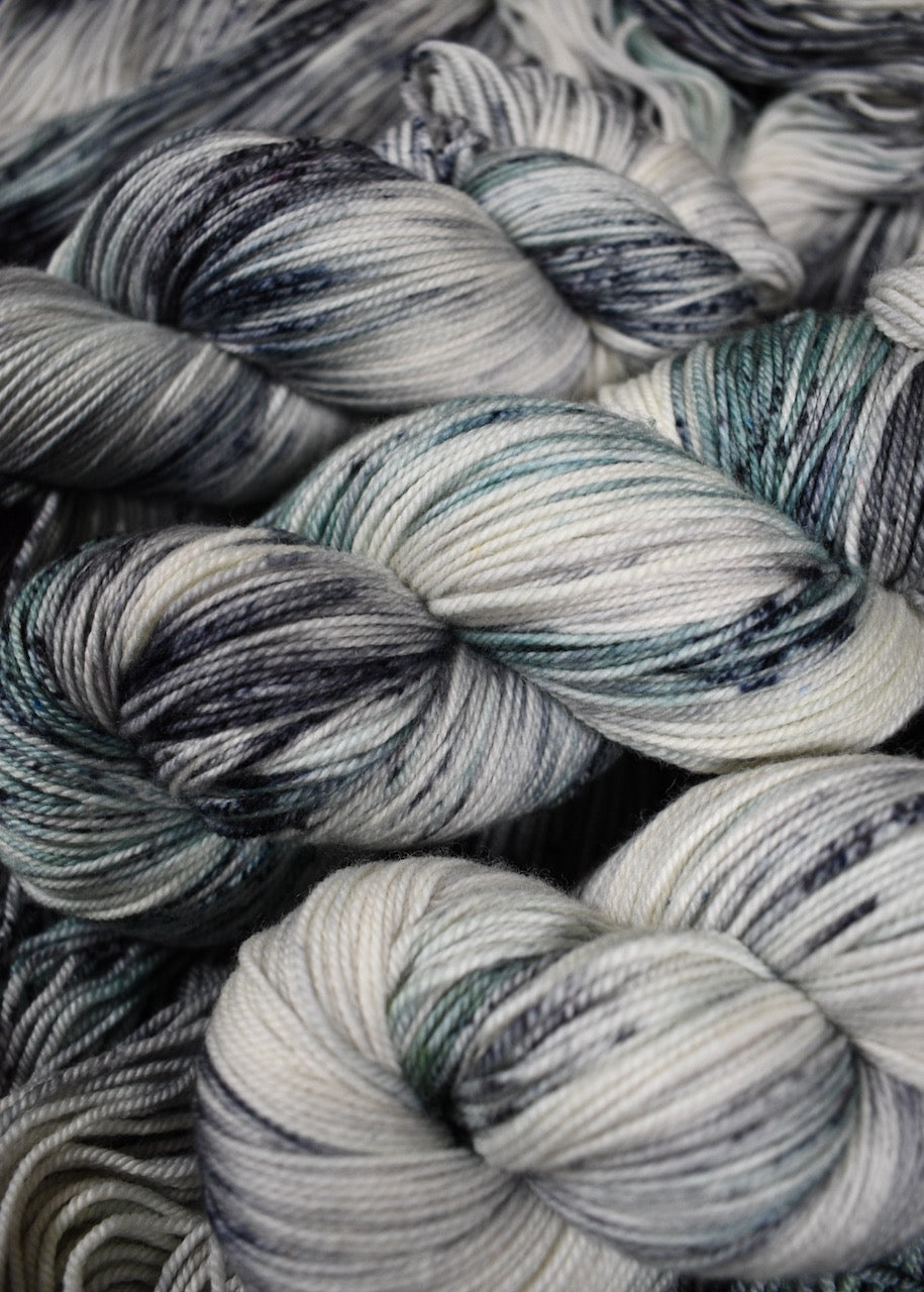 Gray and light green speckled hand dyed merino and cashmere sock yarn.