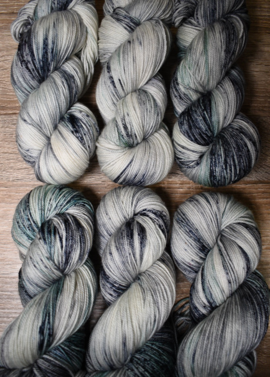 Gray and light green speckled hand dyed merino and cashmere sock yarn.