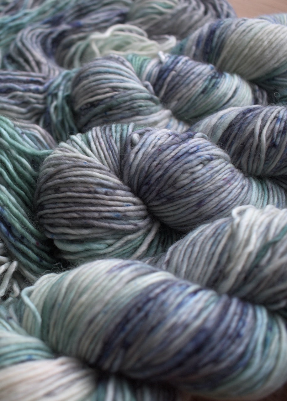 Gray and soft green speckled hand dyed merino yarn.