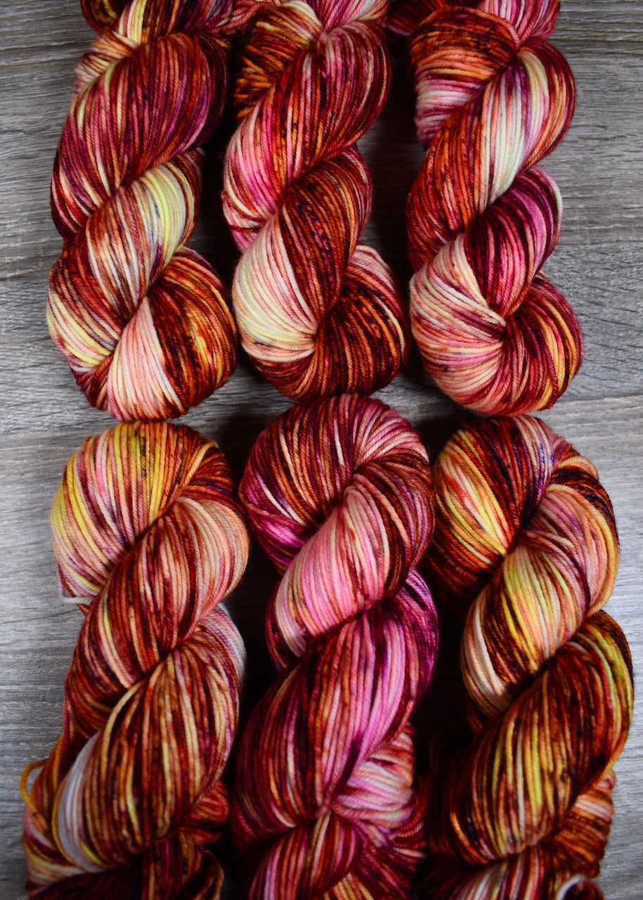 Pink orange yellow speckled hand dyed merino worsted yarn.