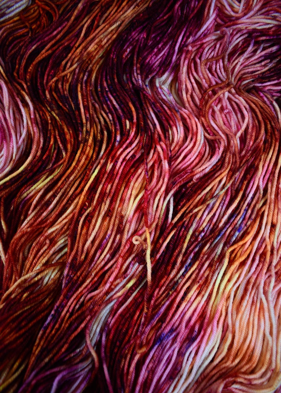 Pink orange yellow speckled hand dyed merino worsted yarn.