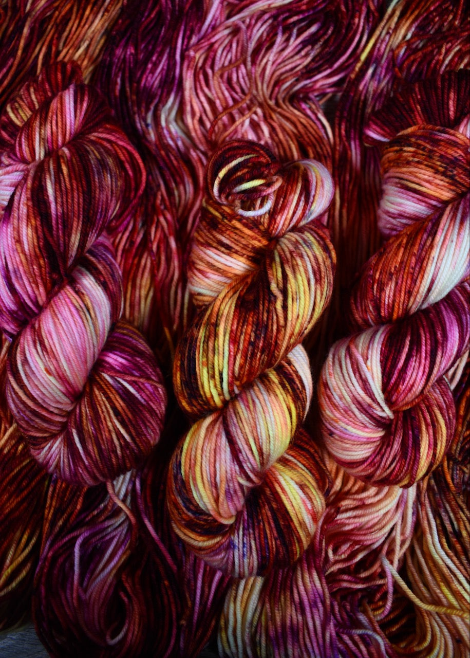 Pink orange yellow speckled hand dyed merino worsted yarn.