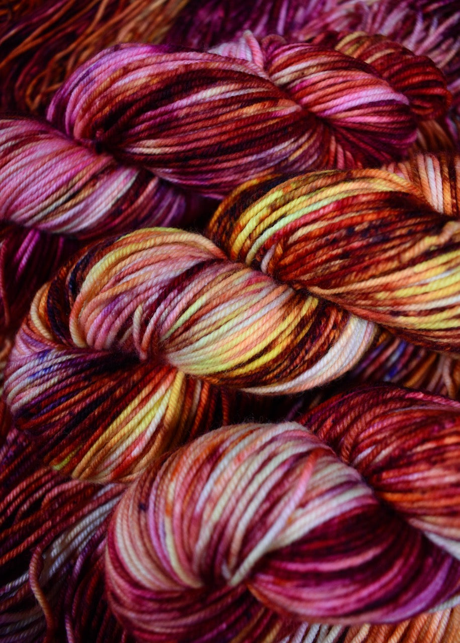 Pink orange yellow speckled hand dyed merino worsted yarn.