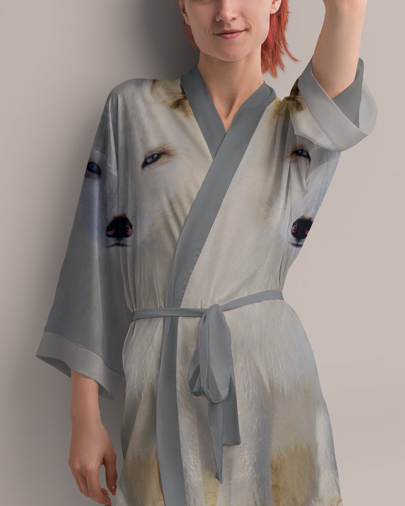 Woman wearing a light gray robe with black arctic fox print on a plain background