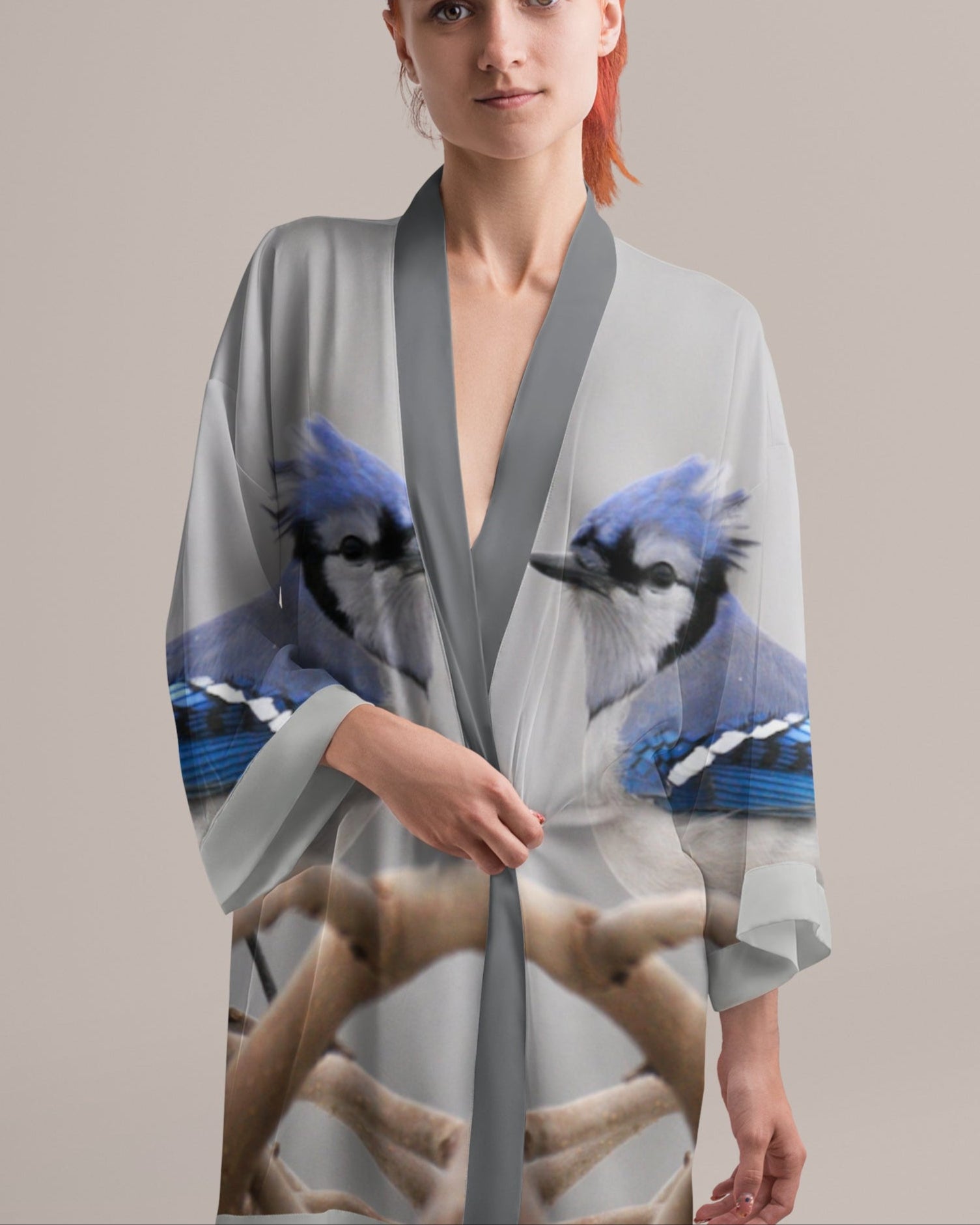 Woman wearing a gray kimono-style garment with blue bird designs on a plain background
