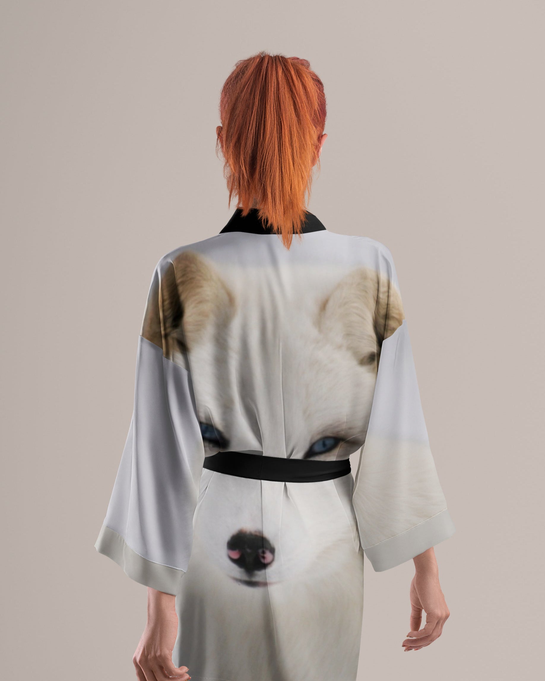 Person wearing a white kimono with animal print of arctic fox on a plain background