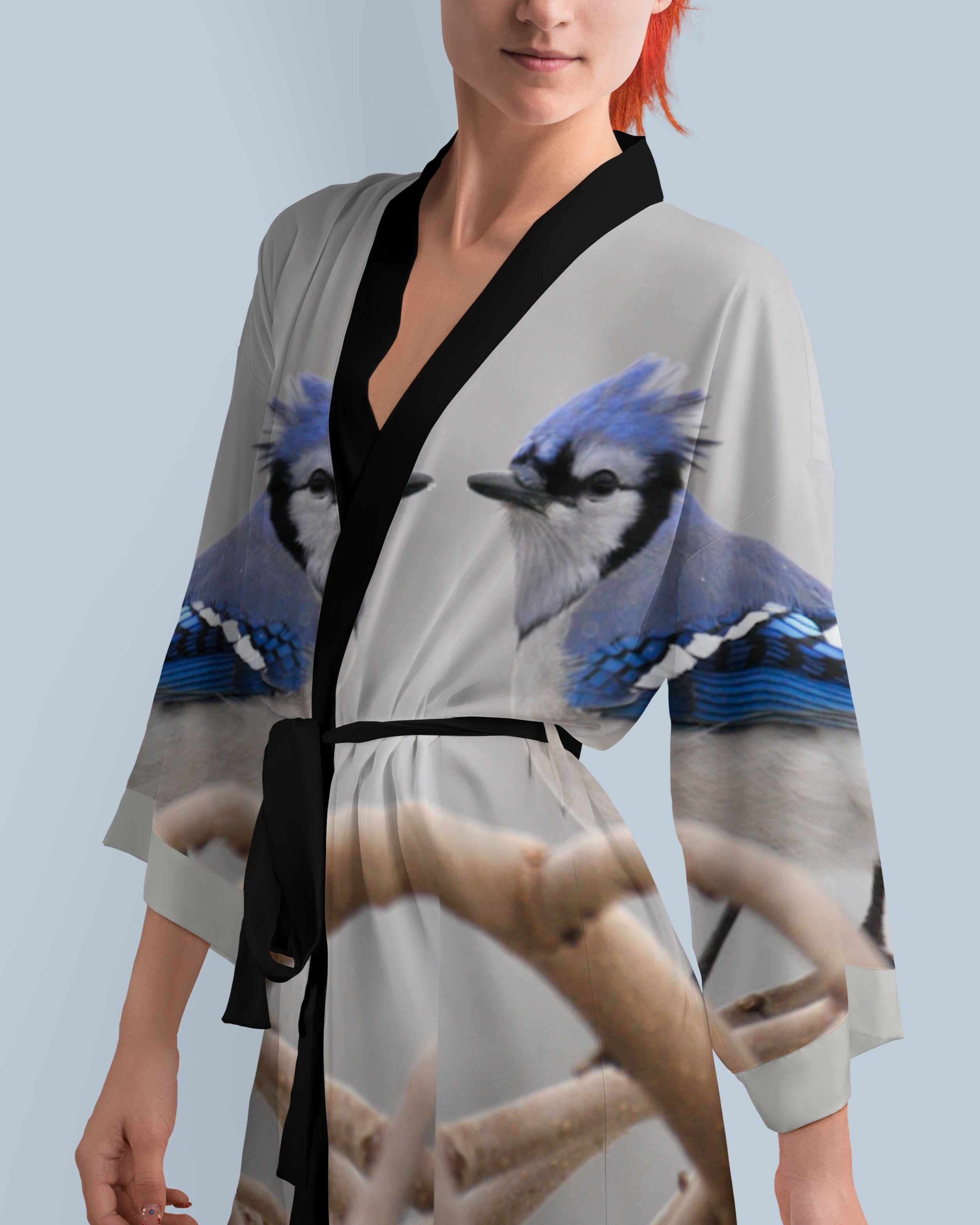 Woman wearing a kimono-style robe with blue jay bird design on a light blue background