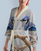 Woman wearing a kimono-style robe with blue jay bird design on a light gray background