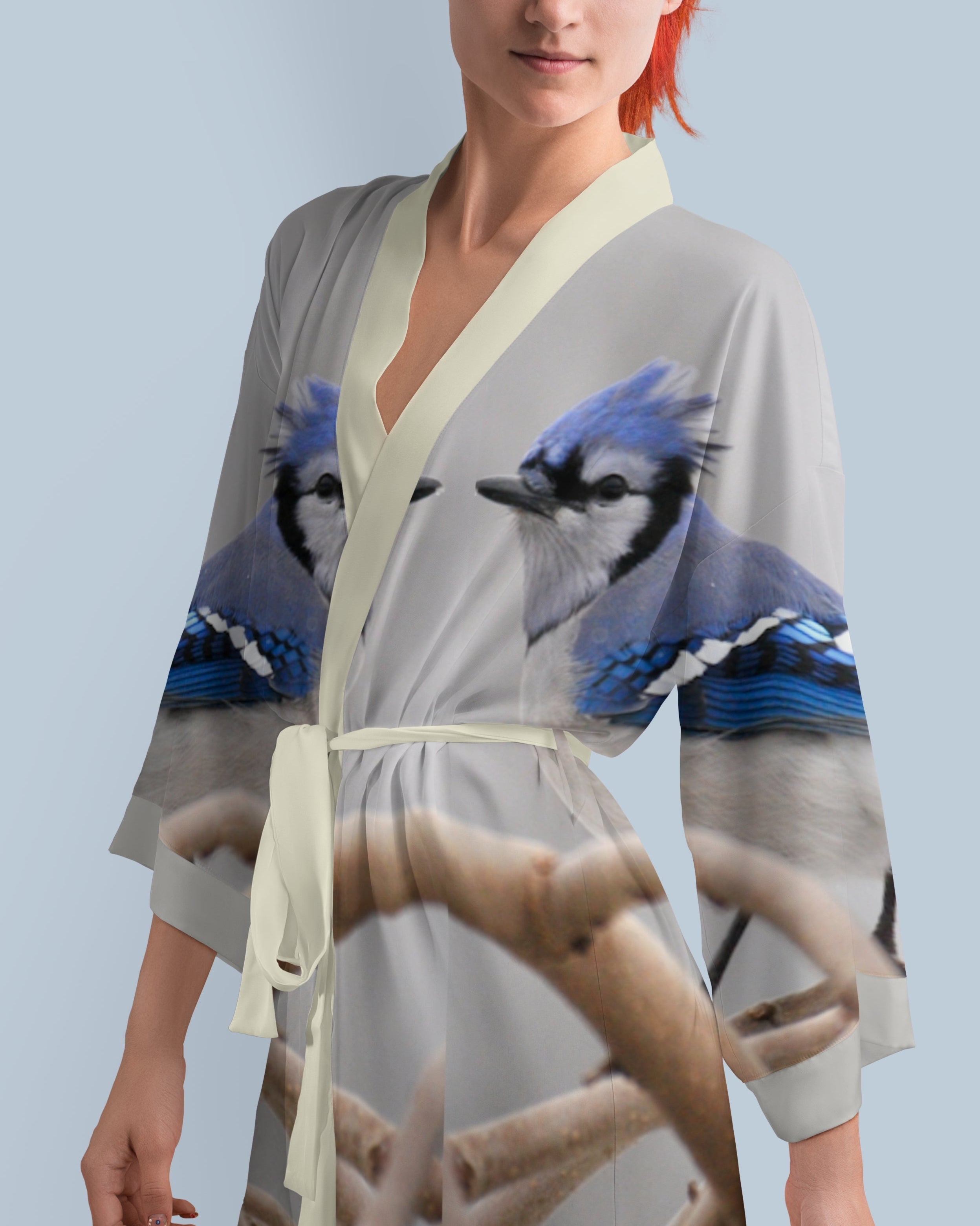 Woman wearing a kimono-style robe with blue jay bird design on a light gray background