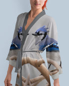 Woman wearing a kimono-style robe with blue jay bird design on a light blue background