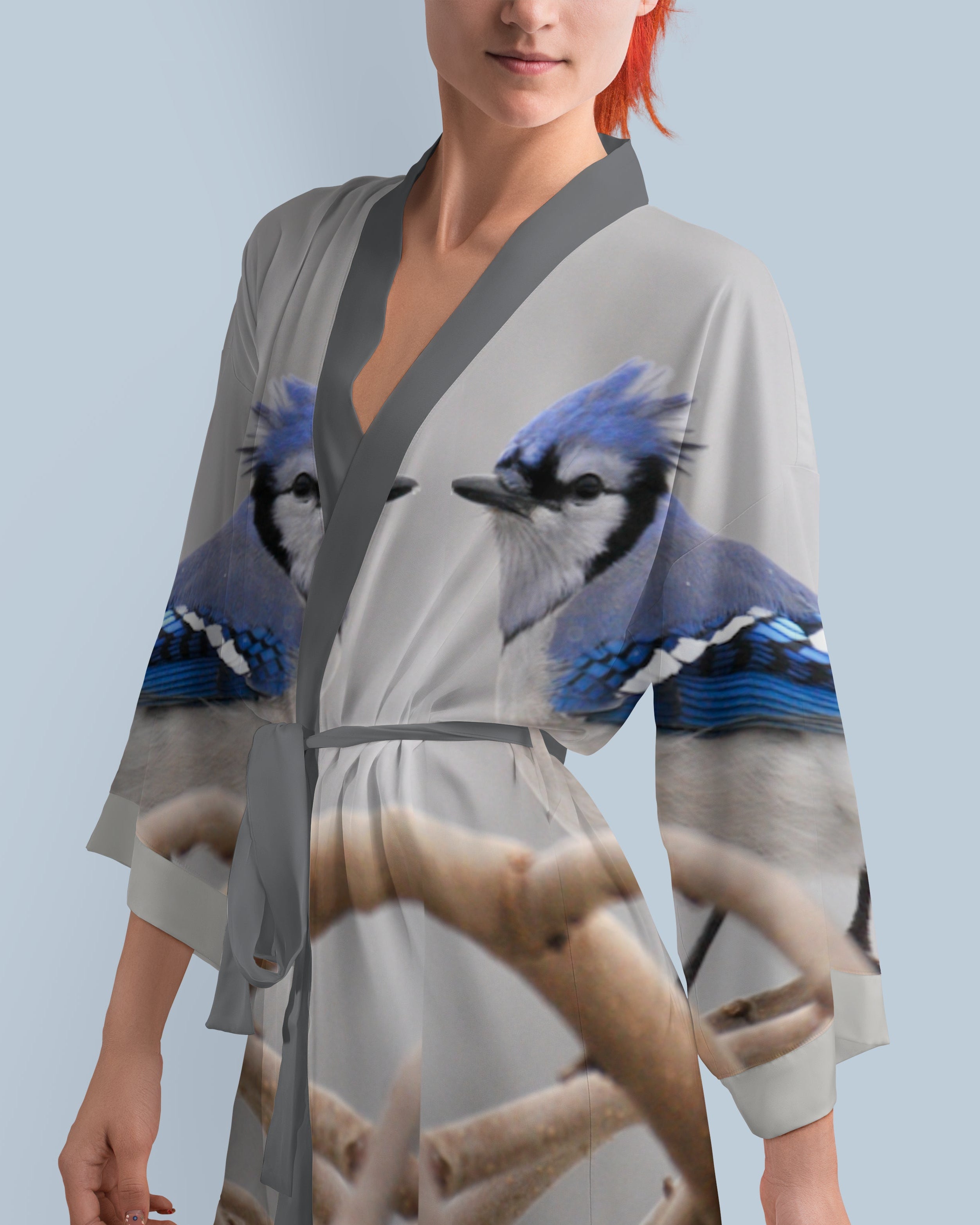 Woman wearing a kimono-style robe with blue jay bird design on a light blue background