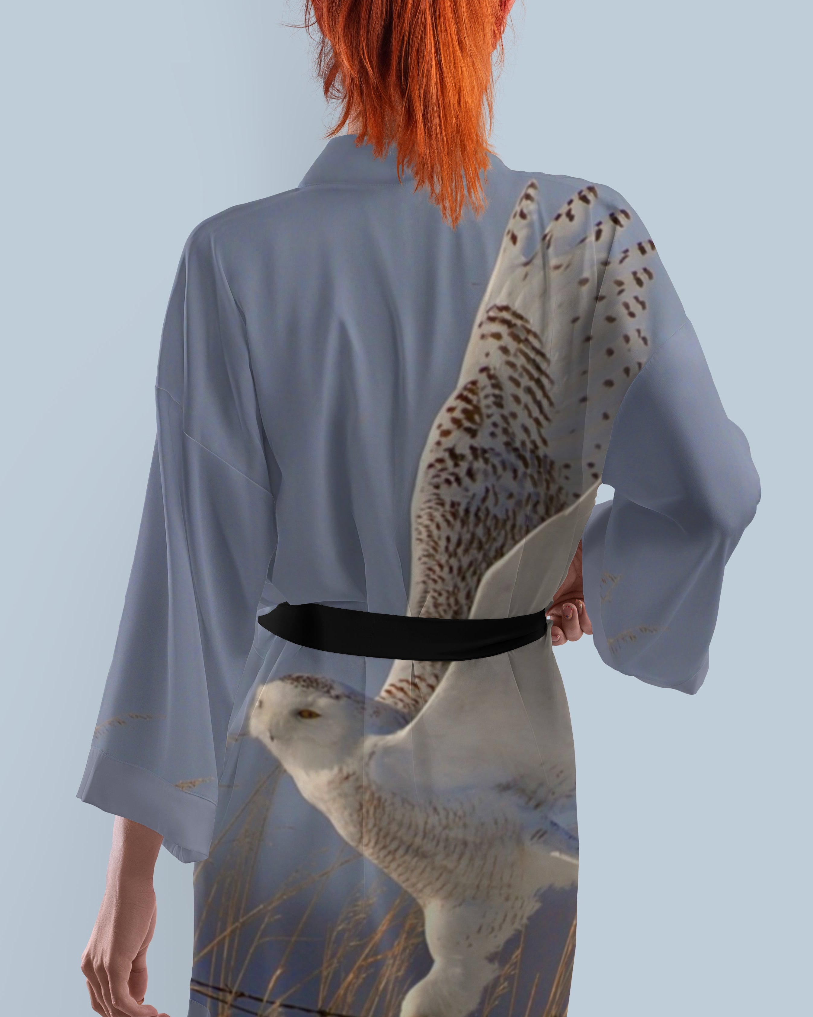 Person wearing a kimono with a snowy owl design on a light blue background.