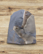Winter hat with a snowy owl design on a wooden surface